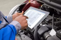 Close-up of mechanic with digital tablet showing graph while examining car.